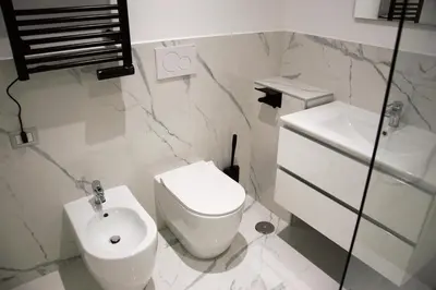 a white bathroom with a toilet and a sink at Domus Dea Roma by Trinità in Rome