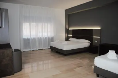 a bedroom with two beds and a large window at Domus Dea Roma by Trinità in Rome