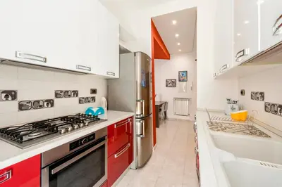 a kitchen with red cabinets and a stove and a sink at Appartamento Amy House in Rome