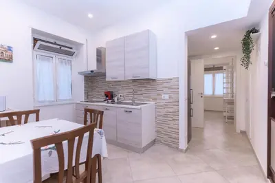 a kitchen with white cabinets and a table and a dining room at Casa Arco in Rome