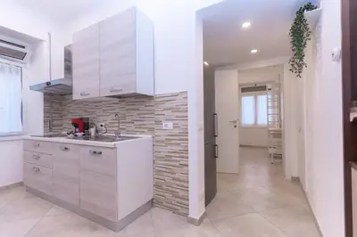 a kitchen with white cabinets and a brick wall at Casa Arco in Rome