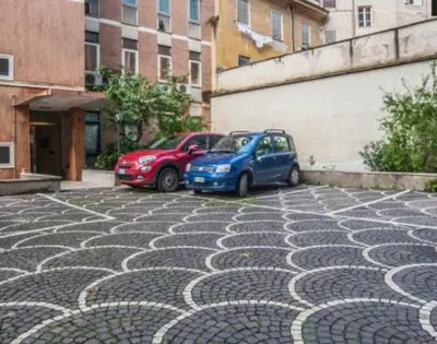 two cars are parked on a cobblestone street at Splendido Attico con Terrazza a Trastevere in Rome