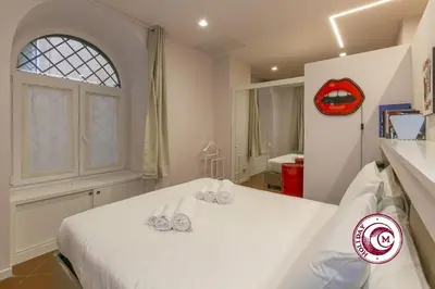 a bedroom with a white bed with a red clock on the wall at C M Barberini Vacation in Rome