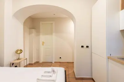a white kitchen with an archway and a white table at Loft nel Cuore della Capitale in Rome