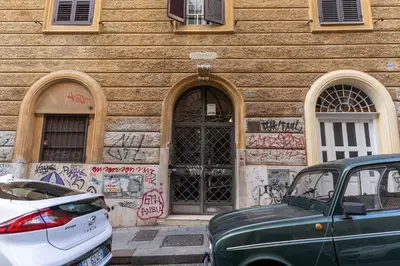 a building with graffiti on it with cars parked in front at Fresh House Sapienza in Rome