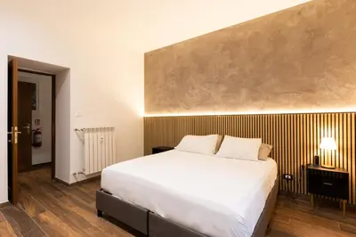 a bedroom with a large white bed and wooden floors at Alma Musa Piazza Bologna Apartment in Rome
