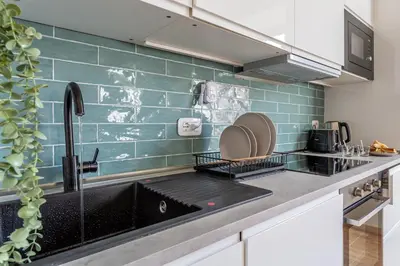 a kitchen with a black sink and green tiles at iFlat Vatican New Bright & Comfy 3 Bedroom apt in Rome