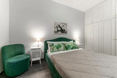 a bedroom with a large bed and a green chair at Francesca Suite - Metro Basilica San Paolo in Rome