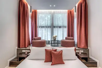 a bedroom with a bed with two chairs and a window at Parioli Cube Hotel in Rome