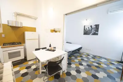 a room with a kitchen with a table and a refrigerator at Eclectic Apartment in Trendy San Lorenzo in Rome