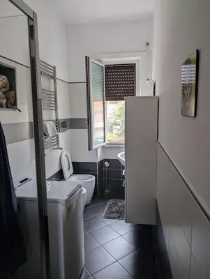 a white bathroom with a toilet and a sink at Spacious and silent two-bedroom apartment in Tor Marancia in Rome