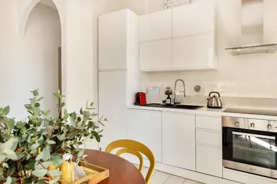 a kitchen with white cabinets and a wooden table at Green apartment Rome in Rome