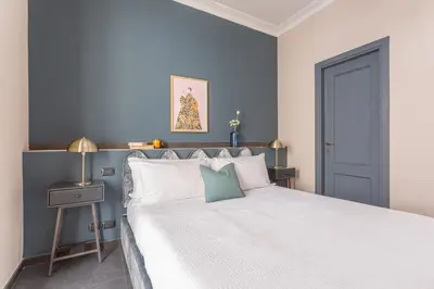 a bedroom with a white bed and a blue wall at Daplace - Cosima Apartment III in Rome