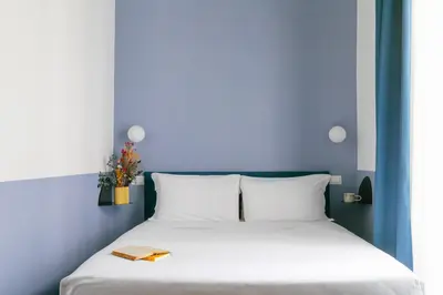 a bed with white sheets and a book on it at Off in Rome