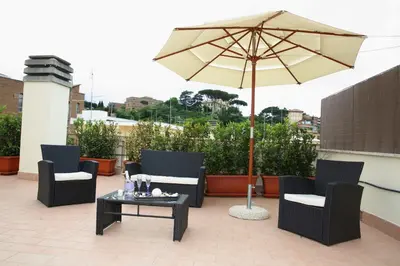 a patio with chairs and an umbrella and a table at L'Isola di Esme in Rome