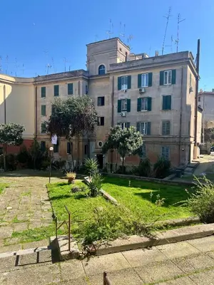 an old building with a grass yard in front of it at Al lotto 27 Garbatella Storica in Rome
