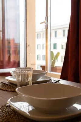 a table with white plates and a glass on it at La Spezia House in Rome