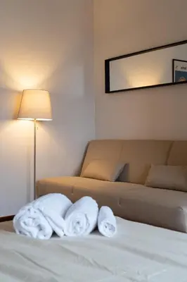 two towels on a bed next to a couch at La Spezia House in Rome