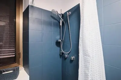 a bathroom with a shower with a blue tile wall at NEW - La Casetta di Nadia in Rome