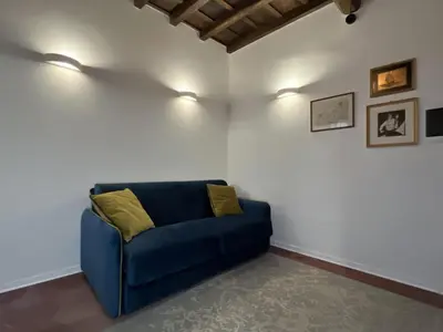a blue couch against a white wall with two lights at Regina Cappellari - Elegante dimora nel cuore di Roma in Rome