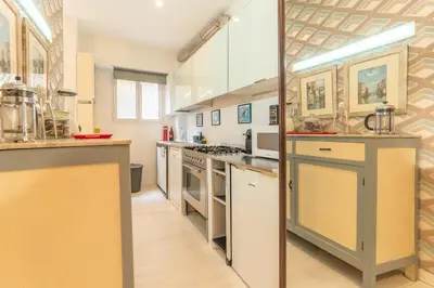 a large kitchen with white counters and appliances at Gianicolo Secret Garden Suite in Rome