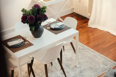 a white dining room table with a vase of flowers at Sweet Heaven Apartment in Rome