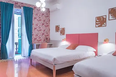 two beds in a room with blue and red walls at Lele Rooms Vaticano in Rome