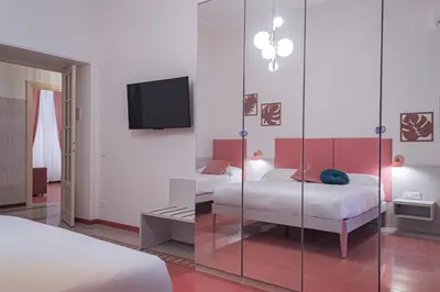 a bedroom with two beds and a tv and a mirror at Lele Rooms Vaticano in Rome