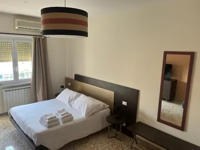 a bedroom with a bed with white sheets and a mirror at Panoramic penthouse 10m from metro A in Rome
