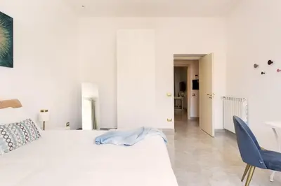 a white bedroom with a white bed and a blue chair at Idyllia - Spacious bright flat in Rome