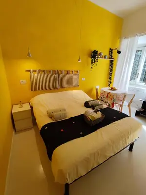 a bedroom with a large bed with yellow walls at COLOSSEUM Studio Flat in Rome