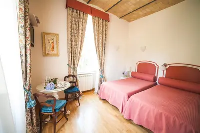 a bedroom with two beds and a table at Villa Paganini B&B in Rome