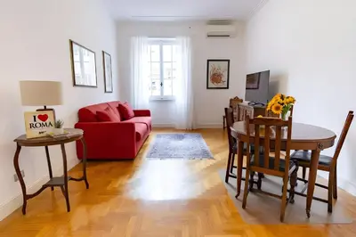 a living room with a red couch and a table at Elegantis Solinda Suite Apartment with Private Terrace - Steps from Metro, Tram & Bus to Rome's Historic Center in Rome