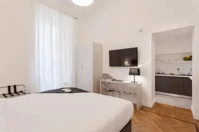 a white bedroom with a bed and a desk and a tv at 504 Corso Suites in Rome