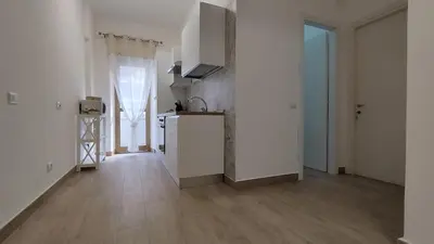 a kitchen with white walls and a wooden floor at 102 DreamHouse metropolitana B Libia in Rome