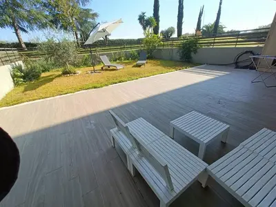 a wooden deck with a bench and an umbrella at Roberta and Luca cozy apartment with garden, terrace and pool in Rome