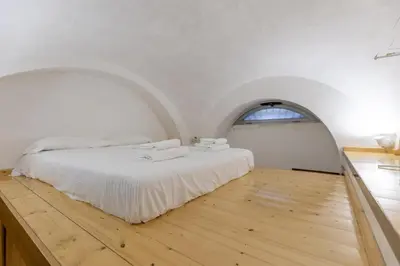 a bedroom with a white bed and an arched window at Monti House - City Center in Rome
