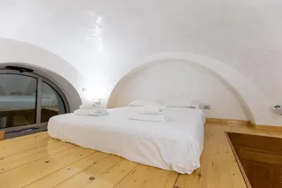 a bedroom with a white bed with an arched window at Monti House - City Center in Rome