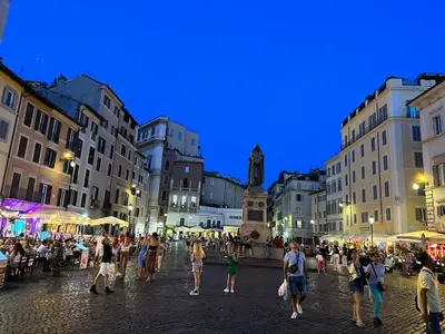 a group of people walking around a street at night at Piazza NAVONA - CAMPO dei FIORI in Rome