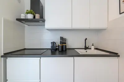a kitchen with white cabinets and a sink at Historic Center - Navona Luxe Haven - Elevator, Soundproof & Netflix in Rome