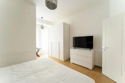 a white bedroom with a bed and a flat screen tv at MP House in Trastevere in Rome
