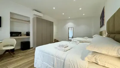 a white bedroom with two beds and a chair at Chich Suites in the Heart of Historic Rome in Rome