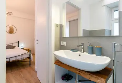 a bathroom with a white sink and a bedroom at Una stanza alPigneto in Rome