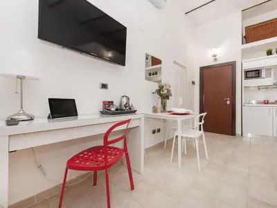 a red chair in a white kitchen with a table at Coral flat Colosseo in Rome