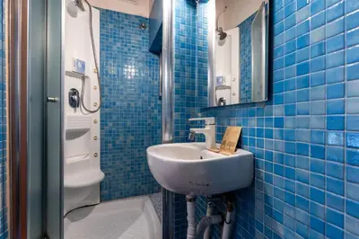 a blue tiled bathroom with a sink and a toilet at La Grande Casa - City Center in Rome