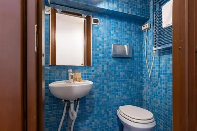 a blue tiled bathroom with a sink and a toilet at La Grande Casa - City Center in Rome
