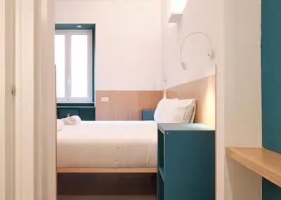 a small bedroom with a bed and a window at Station To Station Rome Ensuite Rooms in Rome
