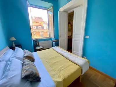 a blue bedroom with a bed with a window at My Varrone Suite in Rome