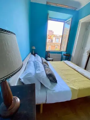 a bedroom with a bed with blue walls and a window at My Varrone Suite in Rome