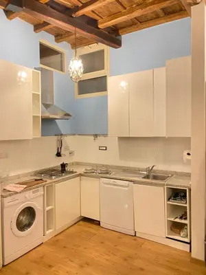 a kitchen with white cabinets and a washer and dryer at Artist apartment in the heart of Trastevere in Rome